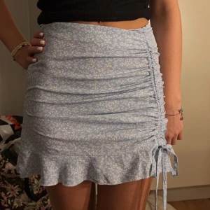 Kort kjol - Blå med vitt blommigt mönster.