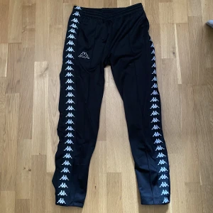 Kappa Byxor - Svarta kappa byxor med knappar på sidan. Inga fläckar eller hål. Säljer på grund av för liten