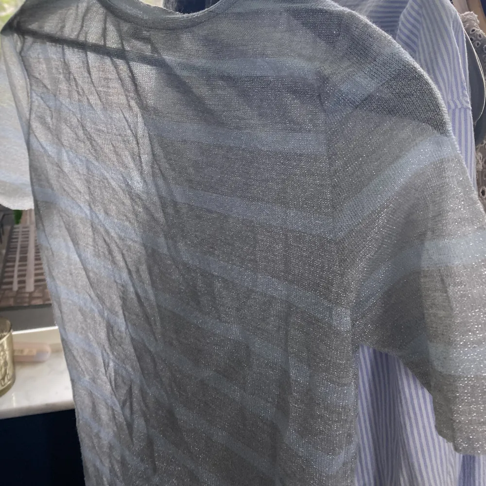 T-shirt i glittrig mesh med ljusblåa och silvriga ränder.  Stretchig i materialet, passar på s/xs men även på M om man vill ha en tight fit. Bra skick. T-shirts.