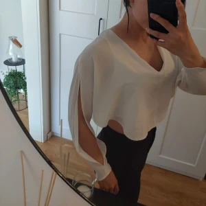 Croppad vit blus - Croppad vit blus med öppna armar. Normal I storleken och endast testad.