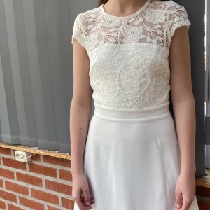 Vit klänning  - Vit klänning ifrån Nelly med spets på. Öppen rygg och väldigt bekväm. Passar perfekt både till student, avslutning eller konfirmation! Endast använd 1 gång 