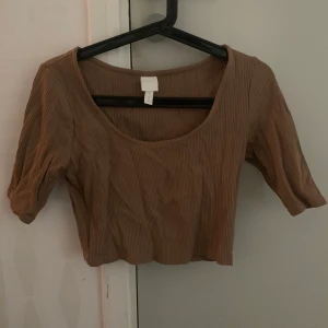 H&M crop top i brun - Säljer denna croptop från H&M eftersom att det har varit i min garderob för länge. Har bara provat på den. Helt ny och fresh. Storlek M