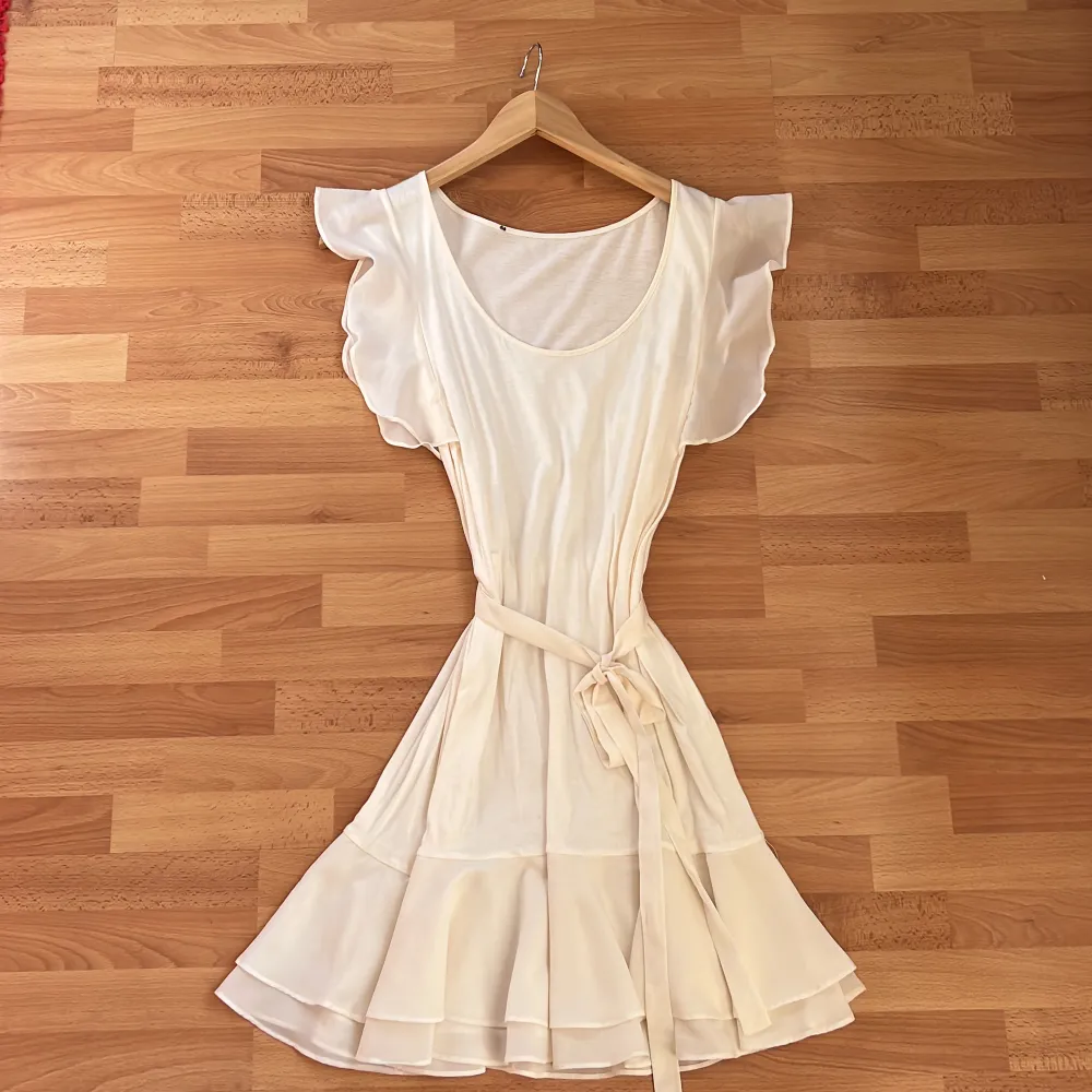 En beige/vit klänning, nästan oanvänd med volanger . Klänningar.