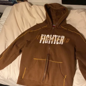 Fighter heat hoodie - Snygg brun fighter gear zip-up hoodie med snygg gul stitching. Size xl men skulle säga att den sitter mer som size M