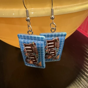 Örhänge M&M - Nya örhänge med M&M. Krokarna är inköpta som nickelsäkra. Köp idag, imorgon kan de vara sålda.