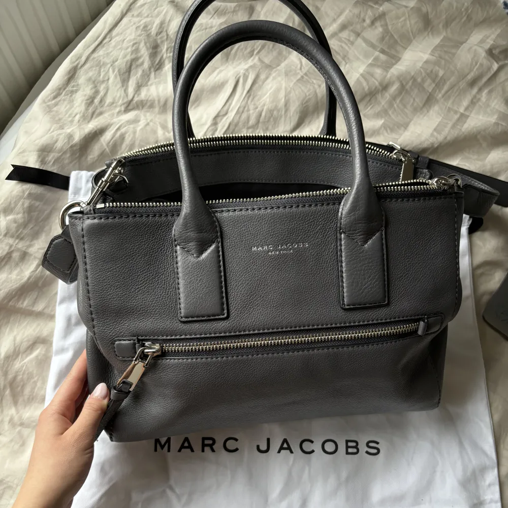 Säljer grå Marc Jacobs väska i skinn då den inte riktigt passar mig. Väskan är knappt använd, NYSKICK🩷Får plats med mycket som t.ex. en dator och massa annat. Vid frågor/fler bilder är det bara att höra av sig! Pris kan diskuteras vid snabb affär!🩷. Väskor.