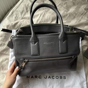 Säljer grå Marc Jacobs väska i skinn då den inte riktigt passar mig. Väskan är knappt använd, NYSKICK🩷Får plats med mycket som t.ex. en dator och massa annat. Vid frågor/fler bilder är det bara att höra av sig! Pris kan diskuteras vid snabb affär!🩷