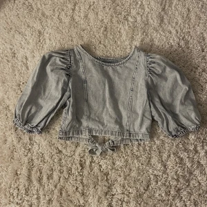 Jeanstopp med öppen rygg - Topp från ginatricot, storlek 38, bra skick, öppen rygg som knyts i bak. Säljer för 130kr