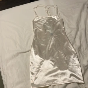 Festklänning  - Jättefin vitskimrande festklänning från hm. Den har cool snörning i ryggen och endast testad!