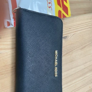 Michael Kors plånbok - Michael Kors plånbok, i fint använt skick, lite av guldpläteringen har gått bort, inga skavanker i övrigt, köpt för 1200kr.