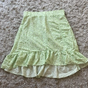 Grön kjol från gina - Ljusgrön kjol med blommor på ifrån ginatricot. Kjolen är i storlek xs och är använd men fortfarande i fint skick.