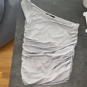 One shoulder top från Gina Tricot  - säljer då den inte kmr till användning. Supersnygg topp från Gina Tricot, i lite glansigt silke material😍 super bra skick, säljer bara för bra pris då jag älskar den🥰nypris 299 min 