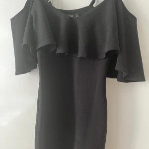 Ursnygg off shoulder klänning - En suuper snygg klänning som är köpt från Nelly. Den är figursydd så den sitter väldigt fint på. Klänningen har volanger. 