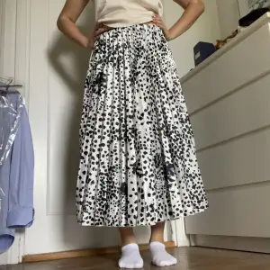 En lång plisserad kjol i vitt med svarta prickar som endast är använd 1 gång. Mycket bra skick och inga defekter. Skriv vid frågor💕