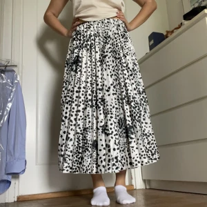 Plisserad Svartvit kjol - En lång plisserad kjol i vitt med svarta prickar som endast är använd 1 gång. Mycket bra skick och inga defekter. Skriv vid frågor💕