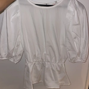 Blus - Vit blus med volanger nedtill, aldrig använd, med prislappen kvar. Tröjan är från Only. 