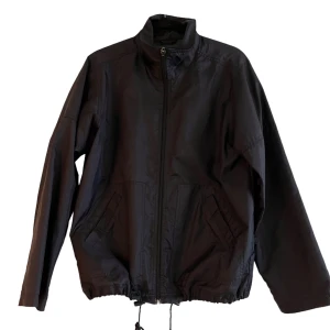 Svart Vindjacka - Svart vindjacka som är cropped, passar Unisex. De snören som hänger ner kan man dra ut vid midjan för att bestämma passform, dem är lite slitna men jackan är i bra skick. 