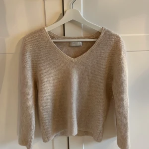 Ljusrosa/beige stickad tröja - Ljusrosa/beige v-ringad stickad tröja, danskt märke. Inte använd mycket ca 3-4 gånger