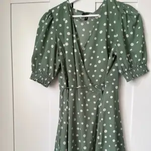 En superfin grön klänning med gröna prickar. Har omlottknytning i midjan/under brösten. Använd några gånger men säljer för jag inte gillar passformen. Frakt tillkommer