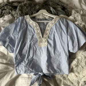 Blå/vit randig v-ringad Zara topp - Blå/vit v-ringad topp från Zara som man själv knyter i ryggen. Fint skick. Storlek M