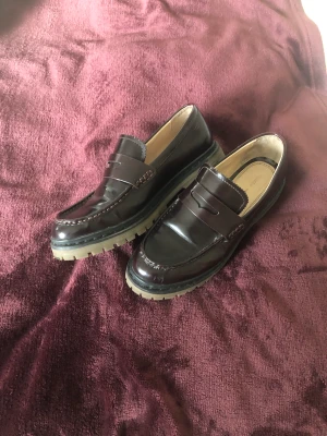 Mörkröda loafers strl 40 - Loafers i gott skick, med några ytliga ripor på sidan. Knappt nötta sulor. Innersulan är 25 cm lång. Dma gärna vid frågor eller funderingar. Köparen står för frakt.