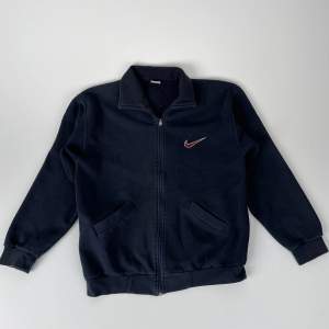 Upptäck tidlöst och ikoniskt sportmode med vår Nike Vintage Zip-sweatshirt. Denna klassiska tröja har en autentisk retrokänsla och är det perfekta tillskottet till din streetwear-kollektion.    Dock ett litet slitage på högra armen 
 
 