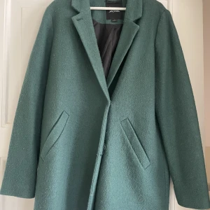 Kappa - Grön kappa från Monki i storlek L som sitter snyggt oversized på mig som är storlek S/M. Lite nopprig och en mindre fläck (bild 3) som inte syns alls när kappan är stängd. Pris exklusive frakt.