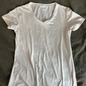 Tshirt - Vit Tshirt med liten v-ringning. Säljer eftersom att den aldeig kom till användning. 