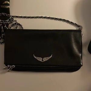 Zadig & Voltaire rock-kuvertväska-noir - Intressekoll på min Zadig Voltaire väska som är i princip i ny skick. Förpackning och extra band medkommer. Köpt för 4100 kr och sälja för 2900kr! Jag är även öppen för byten!
