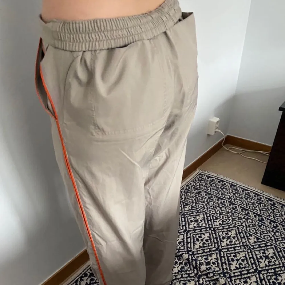 Baggy adidas byxor. Lite gråaktiga, med orangea streck längst sidorna. Strl M men långa. Man kan vika ner kanterna så de blir low waist, super snygga.💕. Jeans & Byxor.