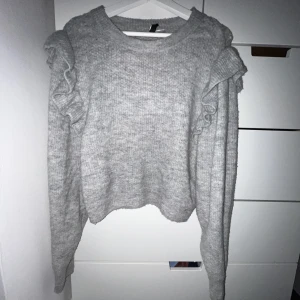 Stickad tröja  - Grå stickad tröja från h&m, med volang vid axeln. I bra skick!!