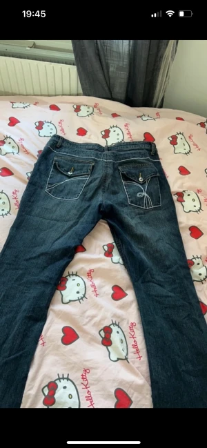 Jeans med fina detaljer på fickorna - Jeans med fina detaljer på fickorna. Lappen på byxorna säger storlek 44 men jag skulle säga att den passar 40/42 mer. 