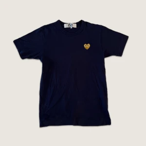 Comme des garcons t-shirt - Kortärmad mörblå Comme Des Garcons tröja med guldigt hjärta! 🧡 vädligt fint skick då jag knappt använt den! storlek S ☆ kontakta mig privat vid frågor & funderingar 🧸 frakt ingår!