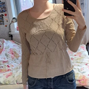 Beige stickad blus - Jättefin långärmad stickad tröja med mönster och knytning från twilfit. Storlek 42/44 men passar som en medium