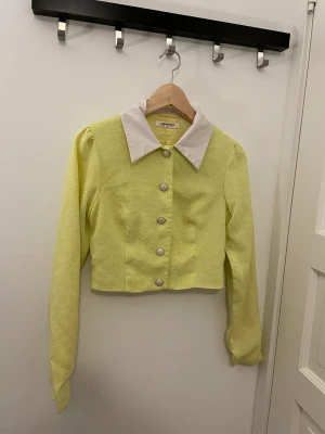 Kavaj  -  En elegant gul kavaj i storlek XS, sparsamt använd och i utmärkt skick. Passar perfekt för olika tillfällen och ger ett stilrent intryck.