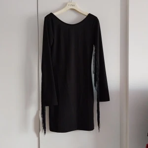 Klänning med fransar - Svart klänning med fransar längs underarmarna. Från HM. Storlek 38. Använd 2 ggr.  Betalning via swish och köparen står för frakten.