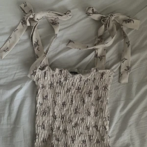 söt topp - Otroligt fin och söt topp från gina tricot! Den har ett blommigt mönster och två axelband som man kan knyta hur man vill (se bild 3). Endast använd 1-2 gånger. Storlek xs men skulle säga att den är liten i storleken och kort, passar xxs-xs. 🌸