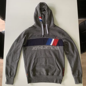 Superdry Hoodie  - Säljer denna grå oversized hoodie av märket Superdry. Trophy tri line, köpt för flera år sedan men ej använts mycket då oversized inte längre är min stil. Storlek S men passar M-L. Väldigt bra skick då den ej använts mycket. Skriv gärna vid frågor. 