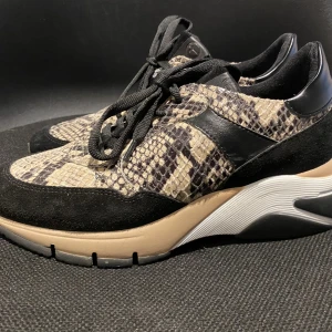 Skor från Tamaris  - Svarta, med leopardmönster. Beige och vitt inslag på sulan. Lite använda.  Storlek 38.