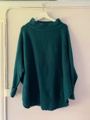 Stickad tröja  - Blandning av tröja och poncho. Superskön på hösten. Säljes då jag har en likadan i annan färg, så denna används inte.  Fint skick.  Typ grönblå i färgen. 