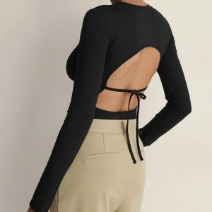 Topp - Ribbad svart topp med knyt i ryggen väldigt strechig och skön. Passar även XS