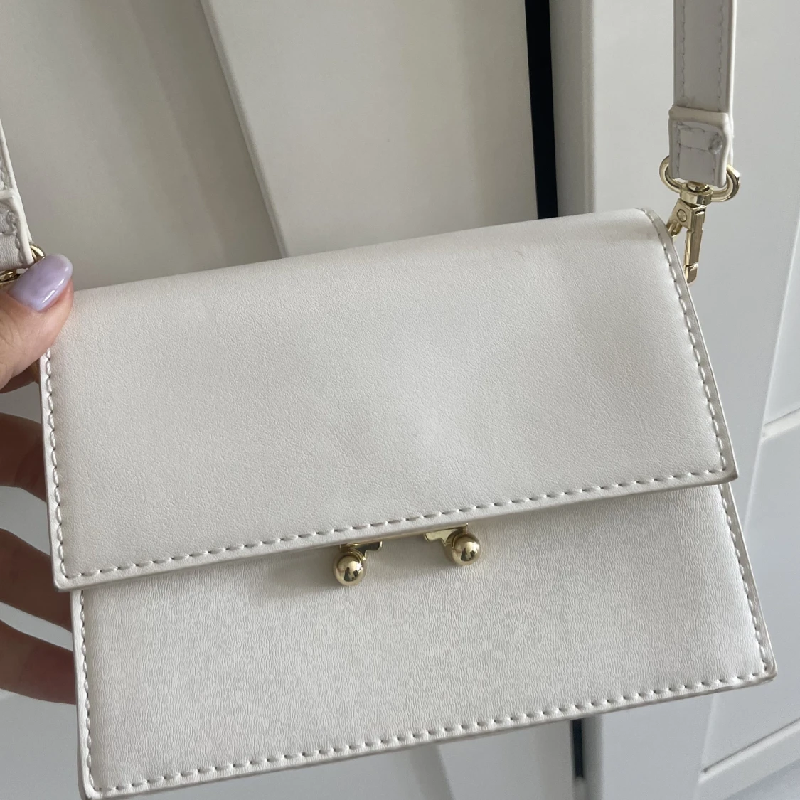 Vit axelremsväska med gulddetaljer