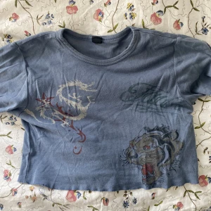 blå crop top - svin cool blå crop-top med snyggt motiv på. köptes på pull&bear i amsterdam, säljer pga brist på användning. 