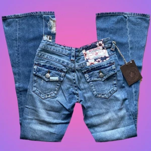 True religion  - Ett par unika vintage bootcut True religion jeans från 2004 med fina mönster av blommor på flera delar av byxorna, prislapp kvar! Skriv om du har frågor!💗