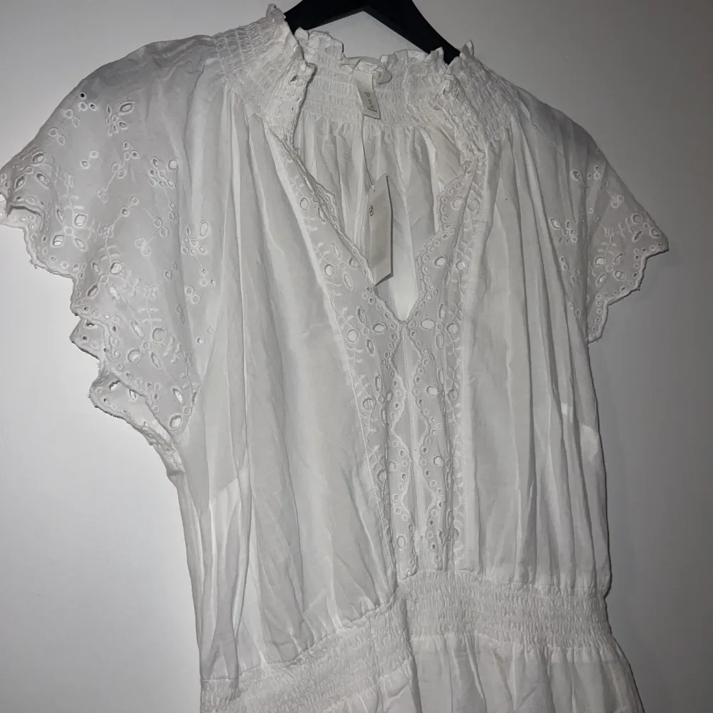 ( Fler bilder kan tas, hel vit i ”vanligt ljus” )  Helt ny klänning från H&M nypris 299kr Jätte fina detaljer dubbel kjol så ej genomskinlig, klänningen är i storlek 40 . Klänningar.