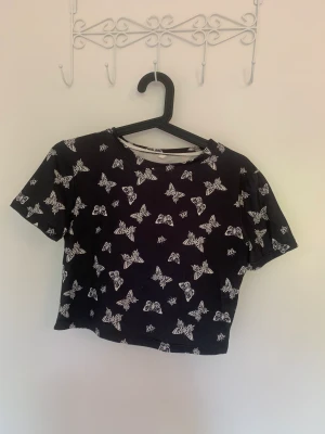 Kort t-shirt med fjärilar - Svart tröja från Shein. Storlek M. Använd fåtal gånger. Skickas med frakt om köparen betalar. 