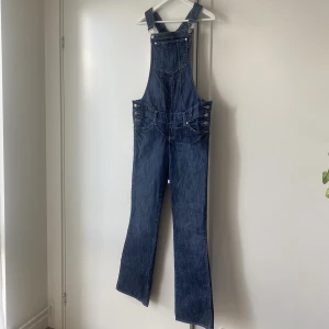 Bootcut hängselbyxor VINTAGE HM - Hängselbyxor med byxa i bootcut-modell. Köpt i vintagebutik, vintage H&M. Storleken är M, men jag som vanligtvis är strl S har bärt dom oversized.