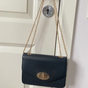 Svart axelväska/handväska  - En svart stilren väska med gulddetaljer. Kan användas på lite olika sätt. Använd ett fåtal gånger, i mycket bra skick.✨