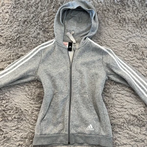 Adidaskofta  - Adidas kofta i storlek 152, passar en xxs. Den har  två fläktar långt ner på ena ärmen därav priset.  