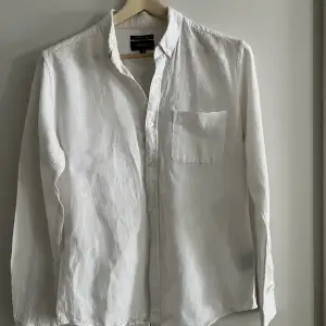 Vit linneskjorta ifrån Crocker. Den grå ”fläcken” till höger är lappen man ser igenom. 